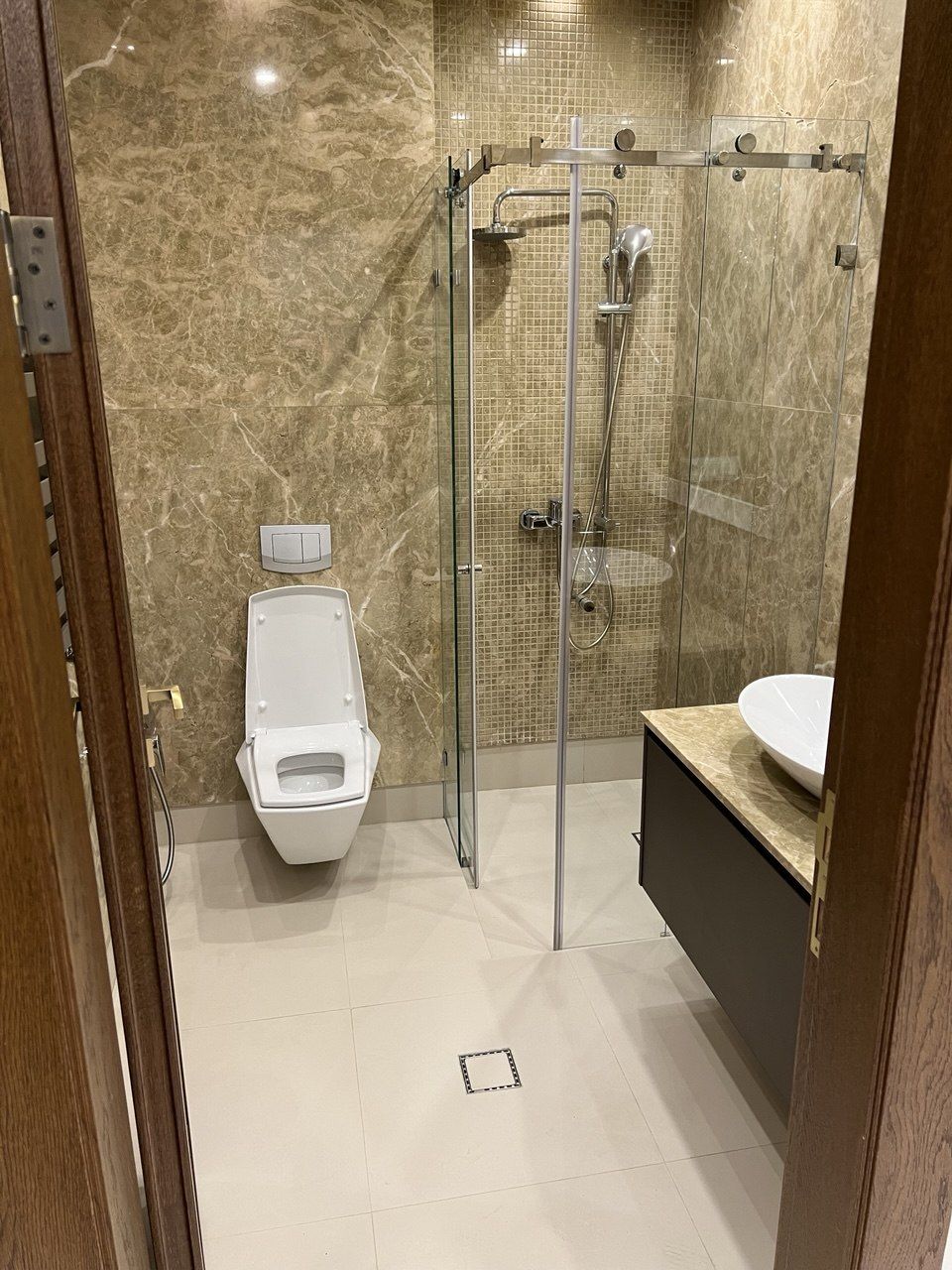 Bathroom with a glass-enclosed shower, wall-hung toilet and stone-clad walls
