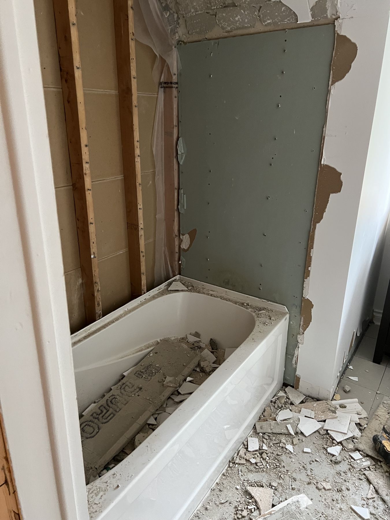 Existing bathroom with the old tub and wall tile coming out