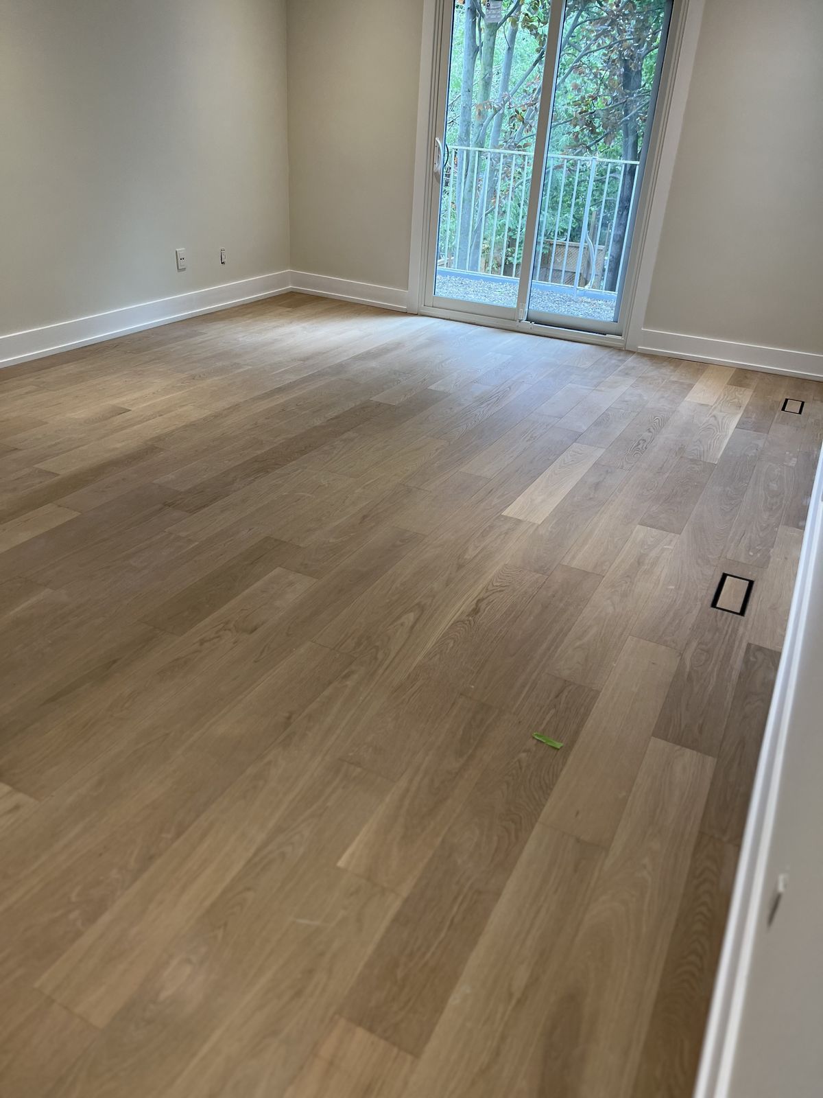 Empty room with new wide-plank oak flooring and a sliding glass door