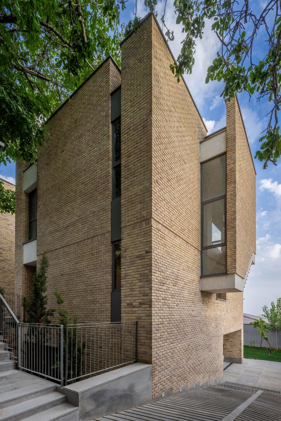 Tall brick house with a narrow corner window, seen from the street